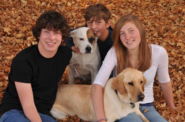 Harold in october 2008 just one week prior to leaving for training Three young people kneel behind two yellow Labrador guide dogs on a carpet of autumn leaves.